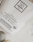 Só Clean powdered laundry soda packaging on a light background with felt dryer balls and some white powdered product.
