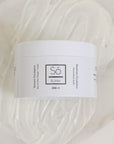 A white plastic jar of Só Butter Rosemary Eucalyptus body butter, placed on top of a textured background of white whipped product