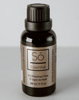 Black bottle of Só Holiday Essential Oil Blend in O' Christmas Tree scent on a light grey background.