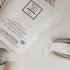 Só Clean powdered laundry soda packaging on a light background with felt dryer balls and some white powdered product.