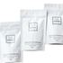 Three white stand-up pouches of Só Cocoa Oat Coconut & Oat Milk Bath 100g arranged from the bottom left corner to the top right corner on a plain white background.