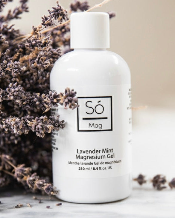 White bottle of Só Lavender Mint Magnesium Gel with lavender flowers on a light background