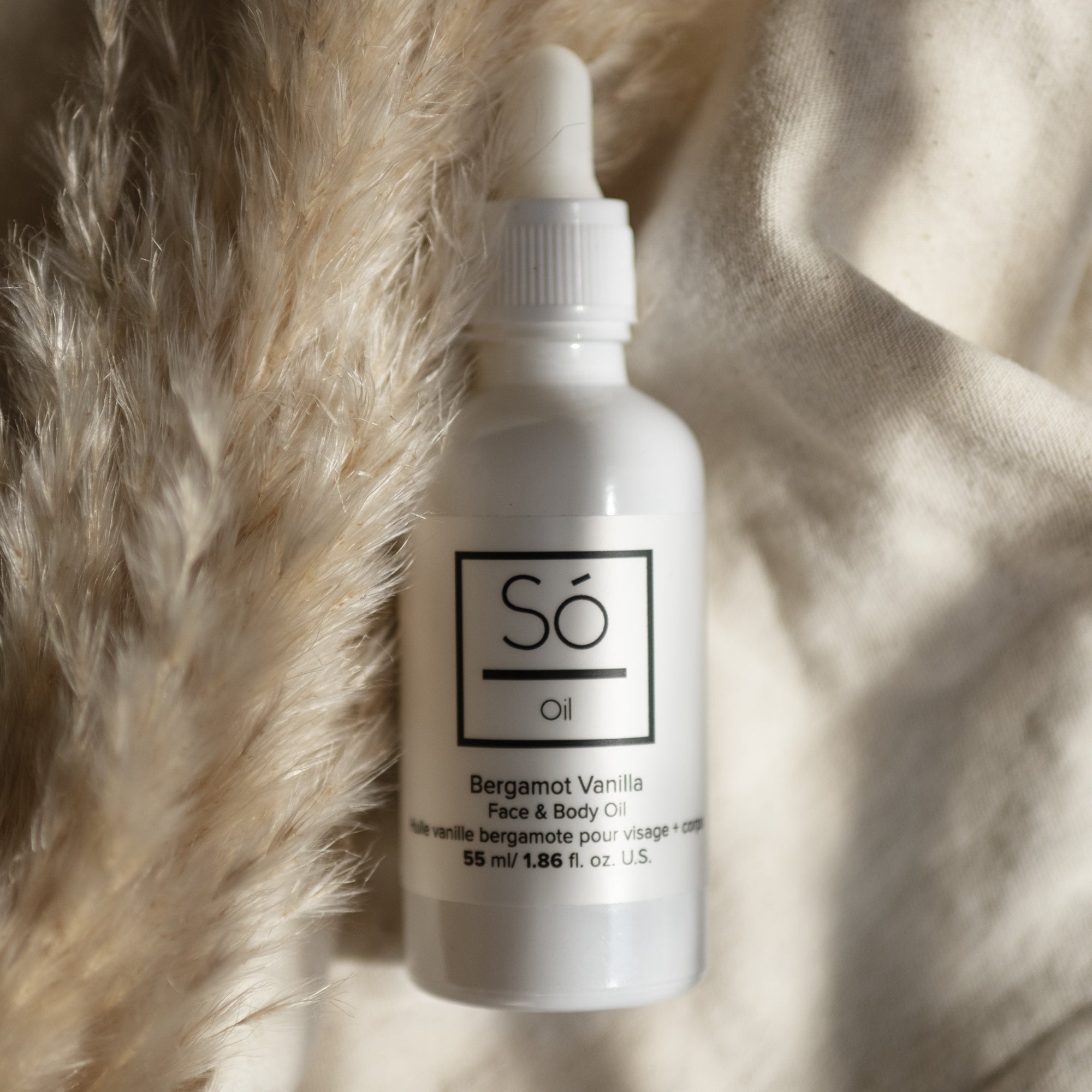 A white bottle labeled 'Só Oil' with fabric and floral elements