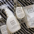 A set of white and clear cleaning products from Só Clean, including Tangerine Dish Soap, Lavender All Purpose Cleaner, Citrus Dish Soap, and a small Lavender Rinse Aid, arranged on a black and white checkered blanket.
