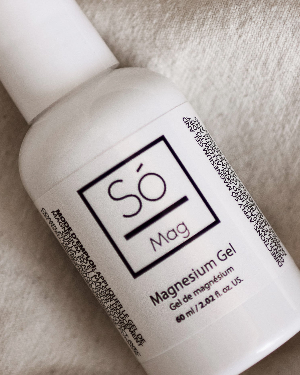 A small white bottle of Só Magnesium Gel placed on a beige fabric.