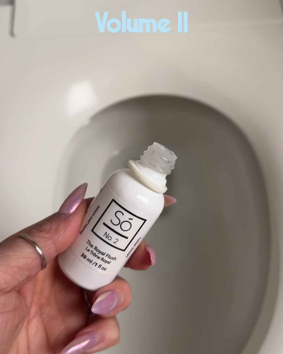 Video showing a hand holding a bottle of Só No. 3 Toilet Drops The Royal Flush over toilet bowl dropping product into the toilet with text overlay on the photo that says "Volume II - Is it Magic or is it Só" and "Makes No. 2s smell like Number Who?"