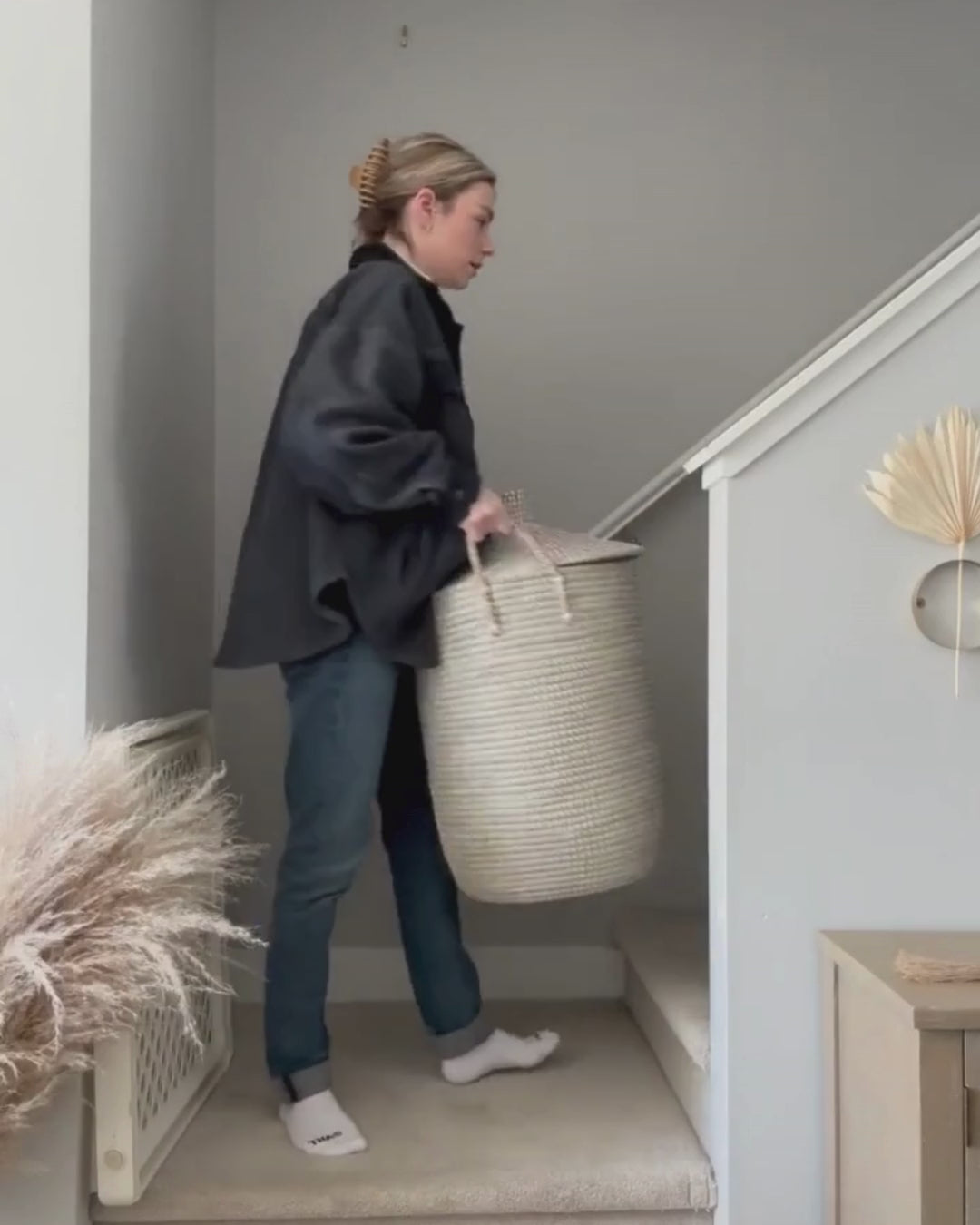 Video showing a woman carrying a laundry basket up the stairs using Só Luxury Stain Remover on her cloth napkins and child's pants to get stains out and showing before and afters of the stains after washing